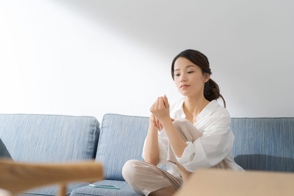 ソファの上で爪を眺める女性