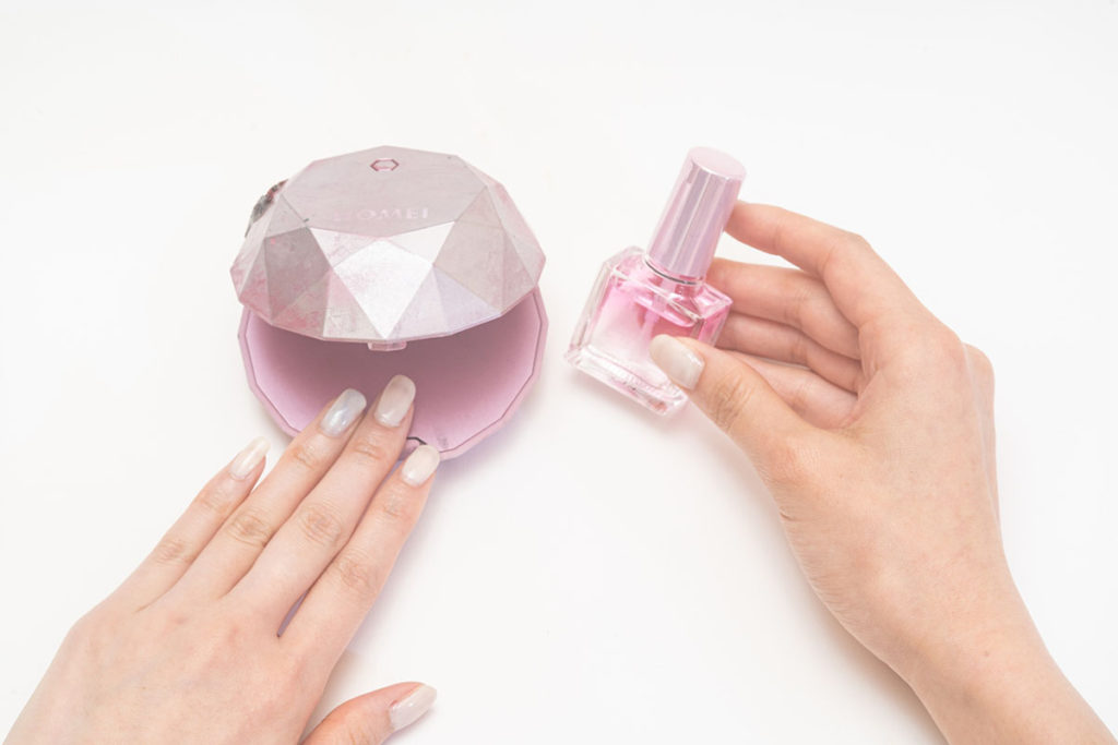 ジェルポリッシュを塗った指をライトに近づけている画像