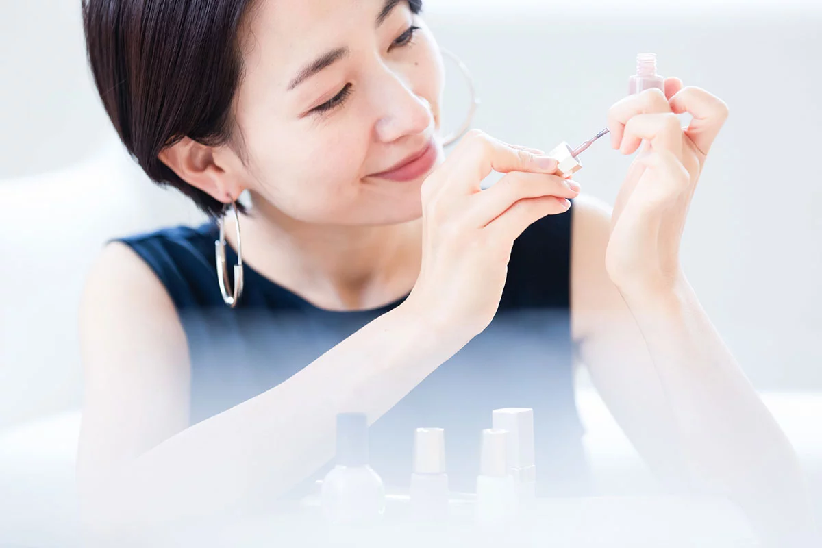 ポリッシュを自分の爪に塗る女性の画像