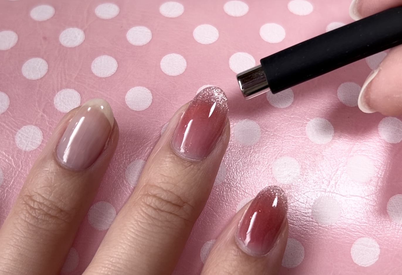 マグネットネイルが塗られた指先に磁石を近づけている様子