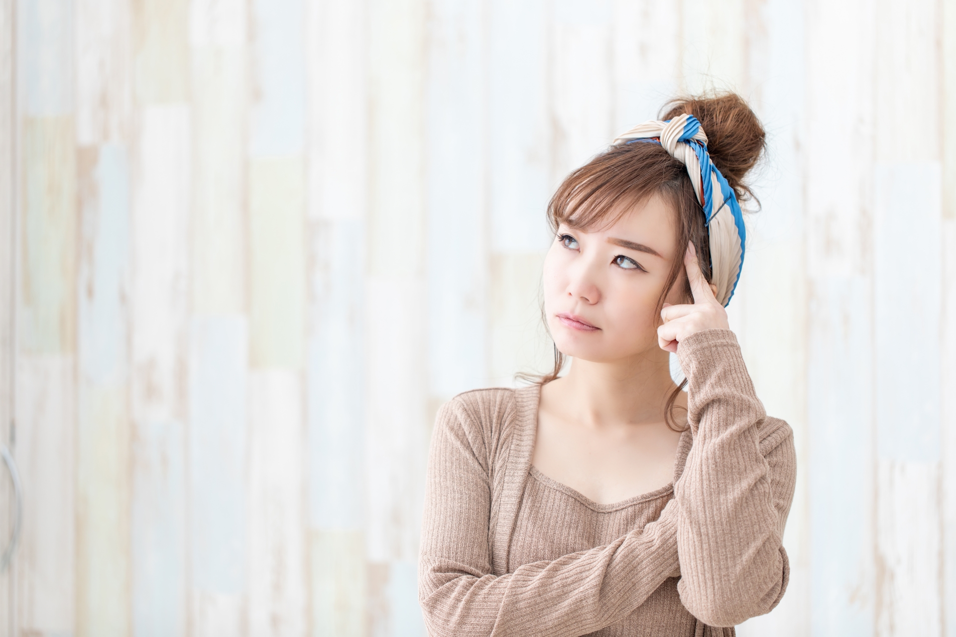 こめかみに指を当て悩んでいる様子の女性