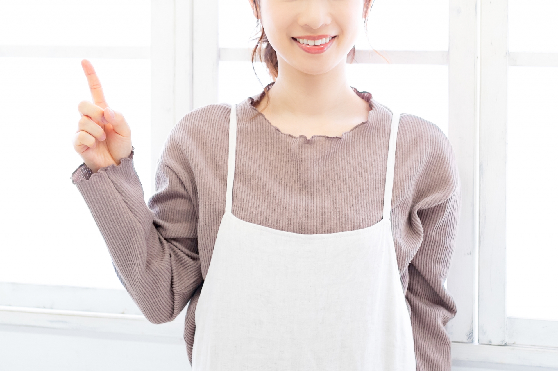 人差し指を挙げてポイントのポーズをする女性
