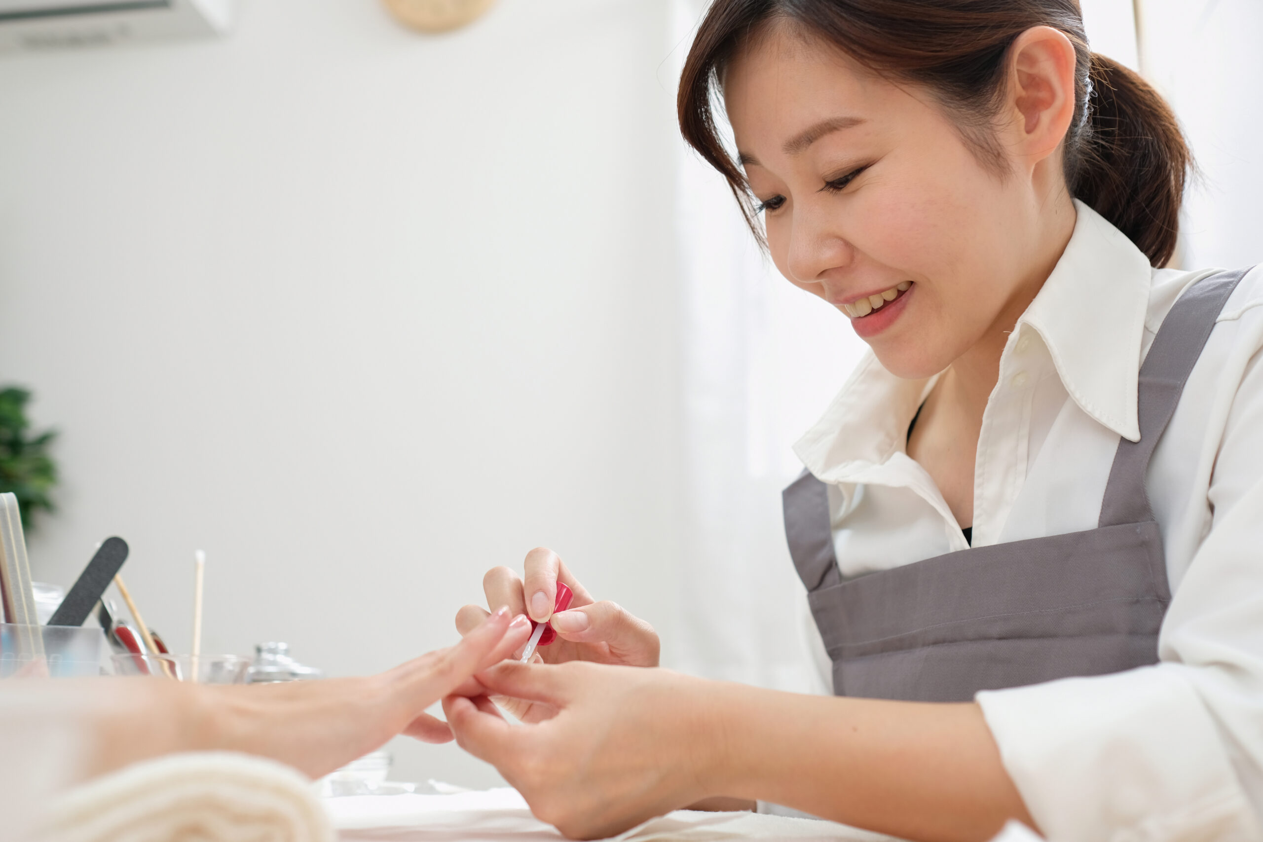 笑顔でお客様に施術をするネイリスト
