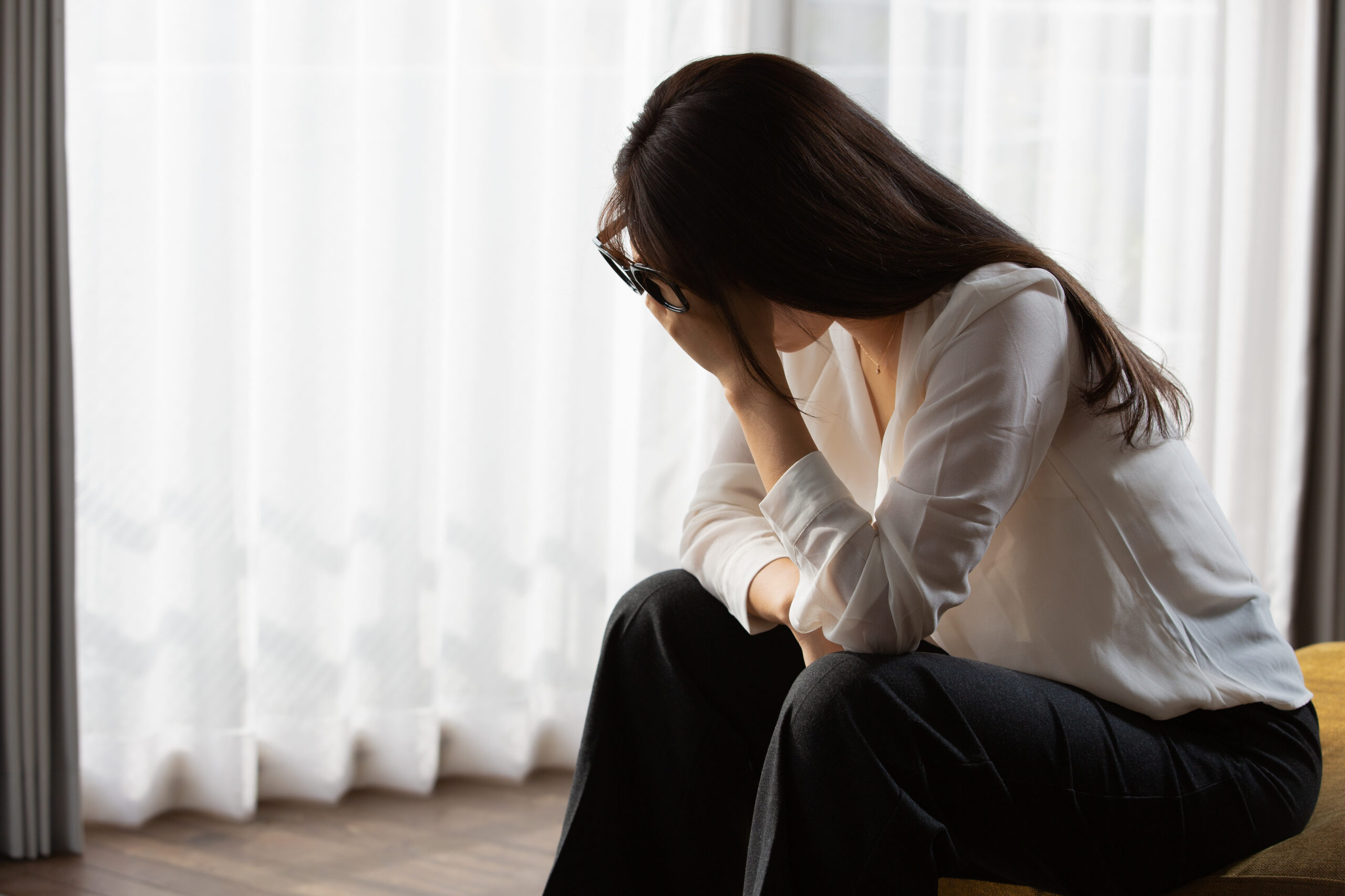 顔に手を当て悩んでいる女性