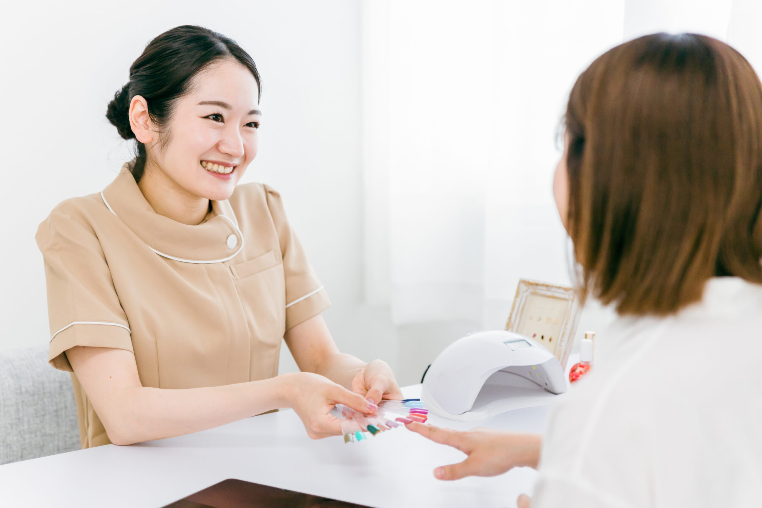 お客様にネイルチップカラーを用いて説明している女性