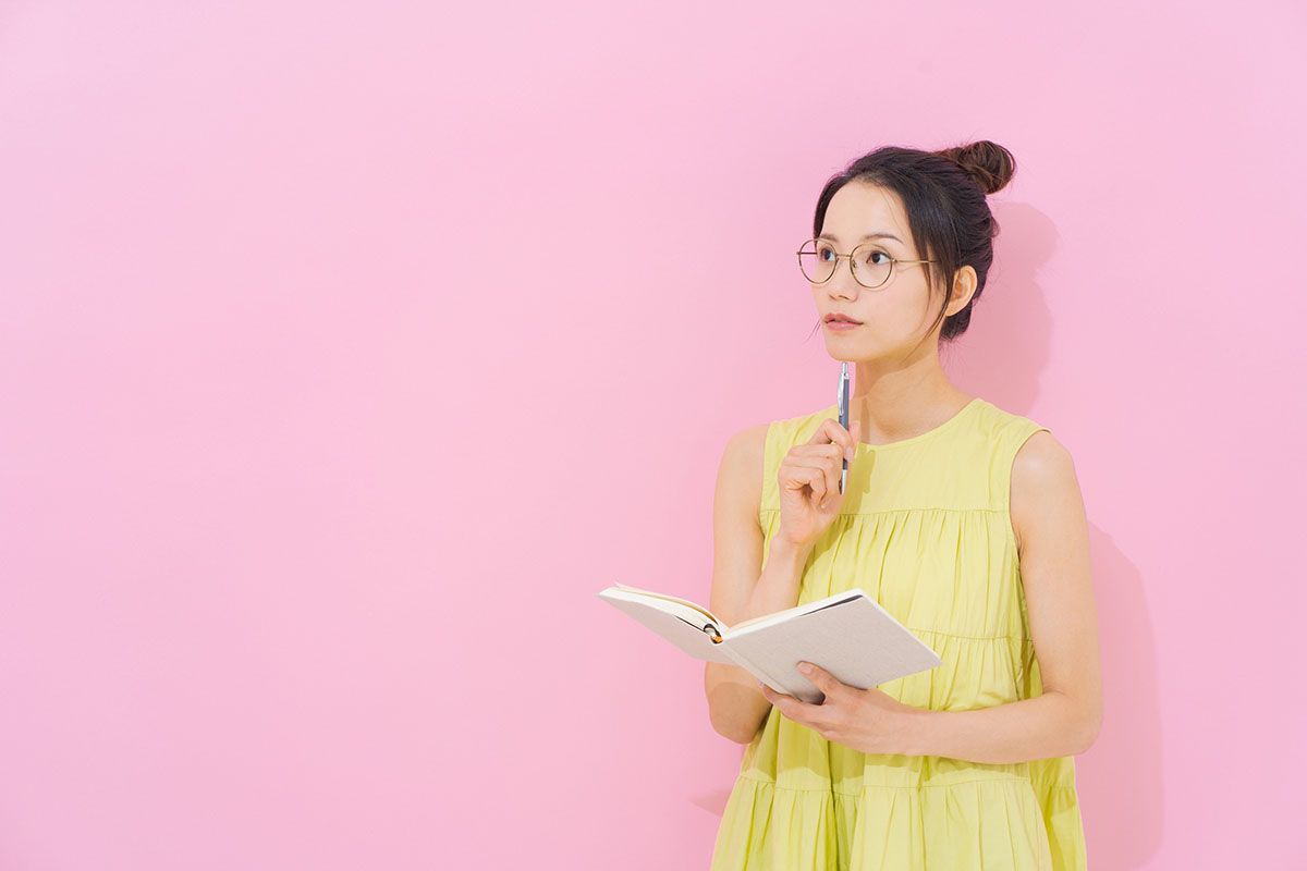 ノートを手に持ち悩んでいる様子の女性