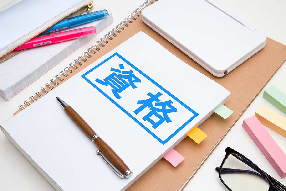 資格と書かれた参考書と文房具類